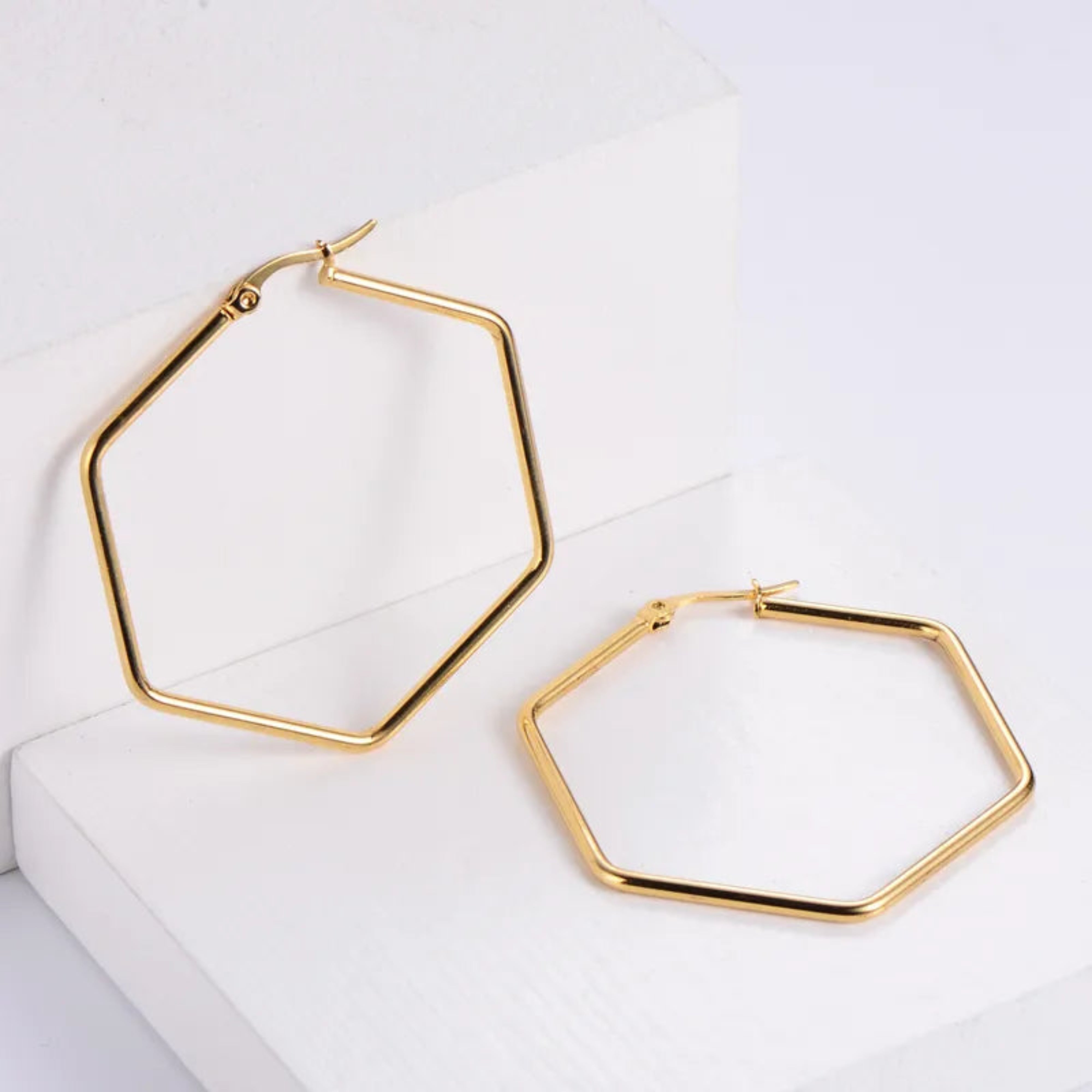 Gold hexagonal hoop earrings on a white background