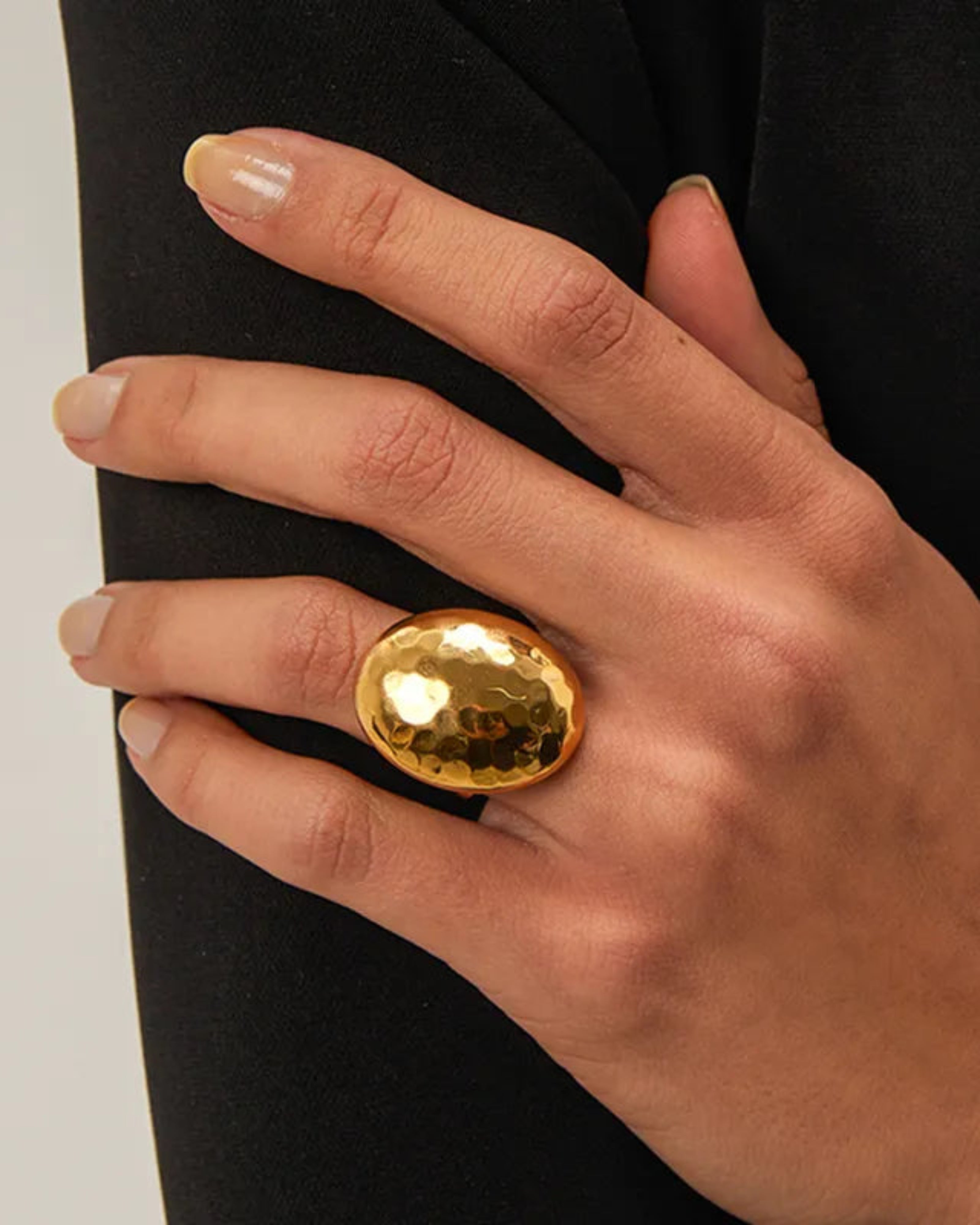 Hand wearing a gold ring on a black background