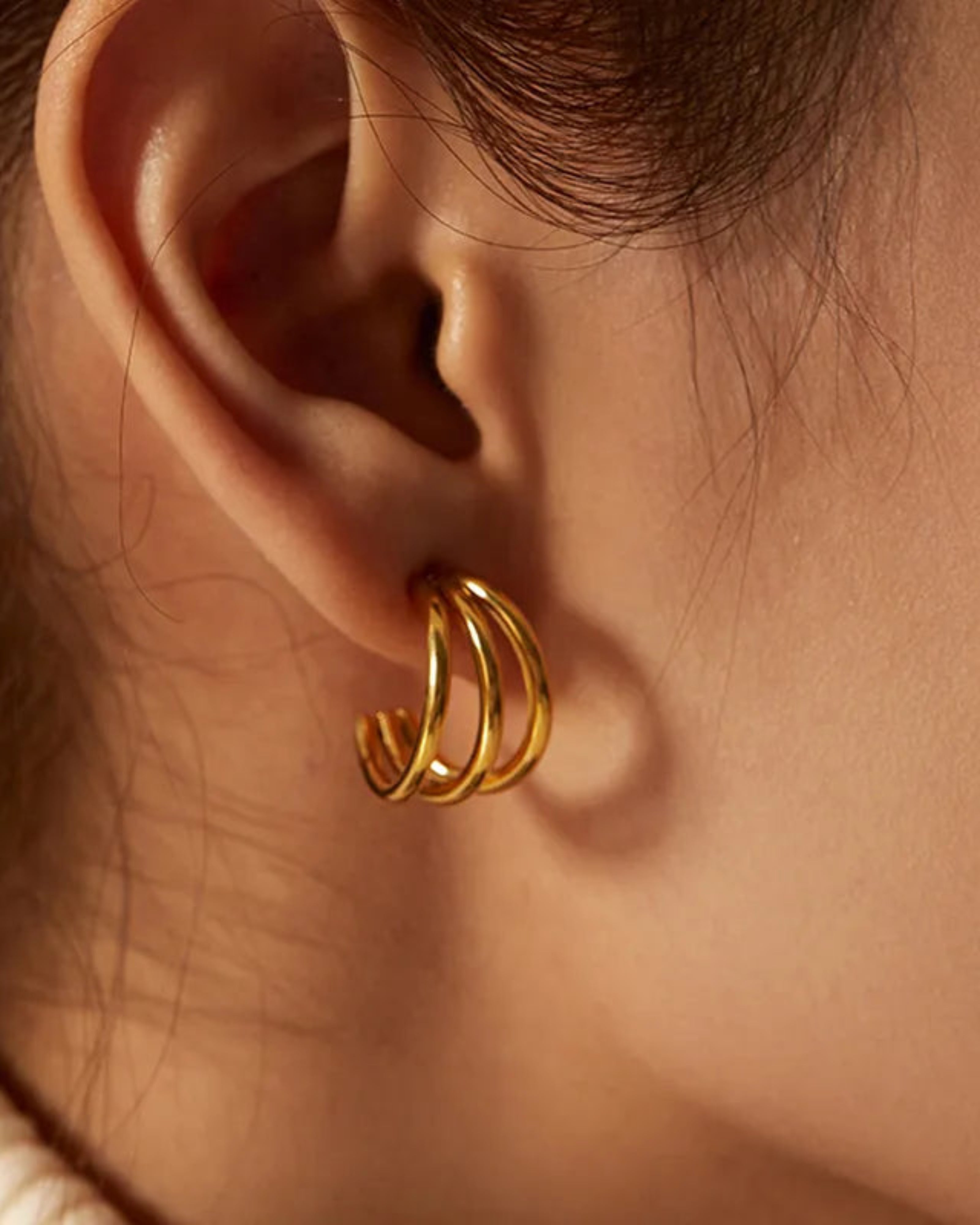 Close-up of a person wearing a gold hoop earring.