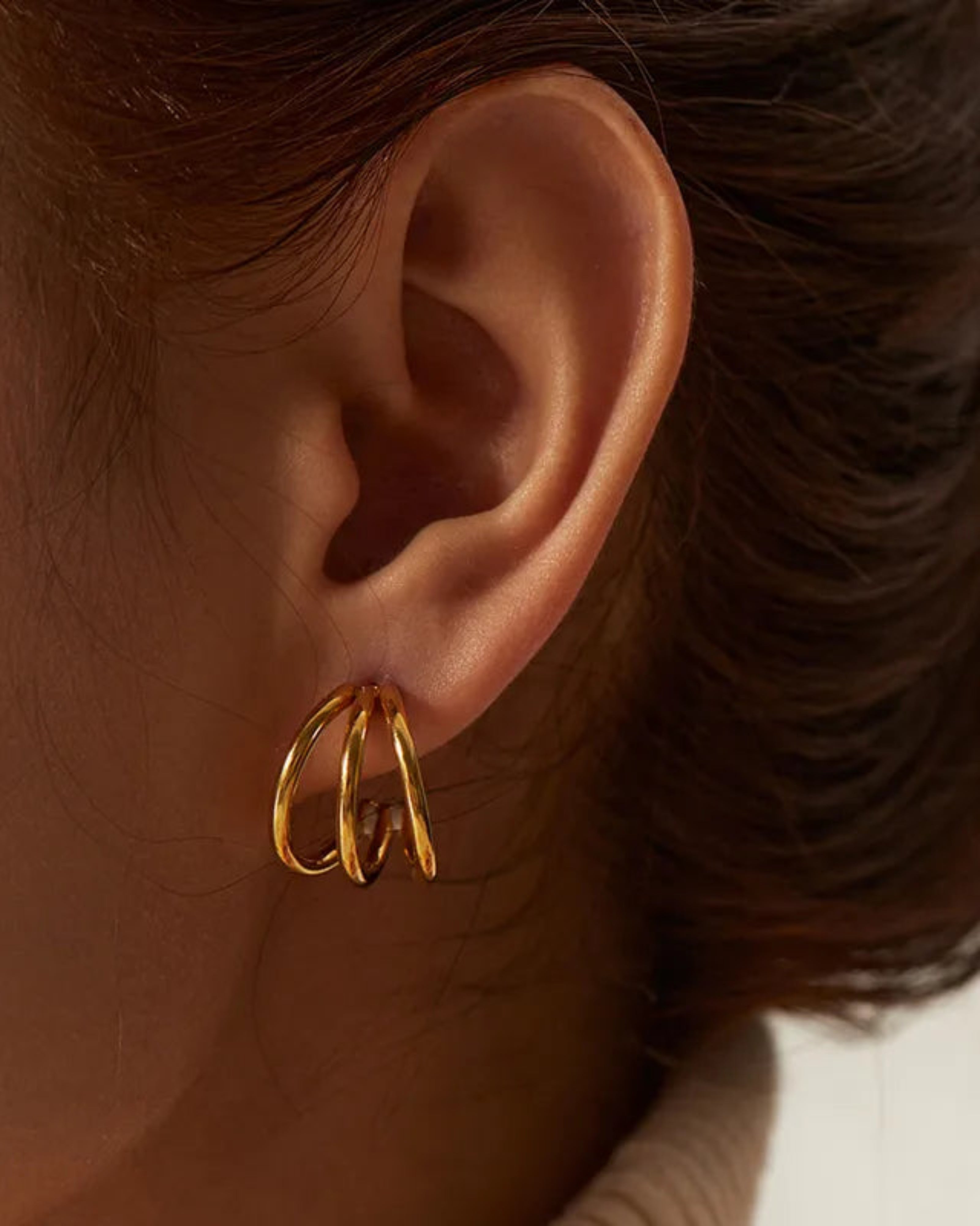Gold hoop earring worn by a person with brown hair.