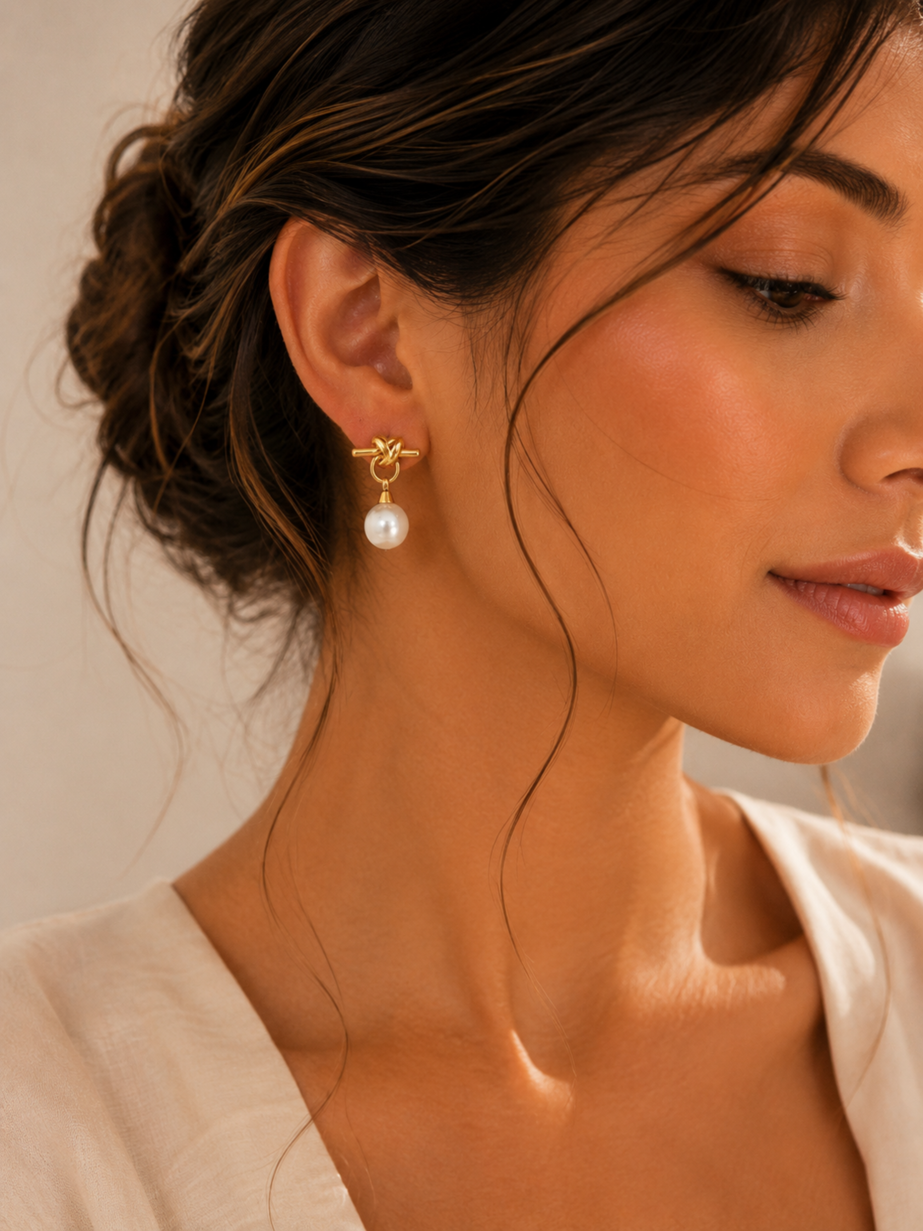 Close-up of a woman wearing pearl earrings with a neutral background