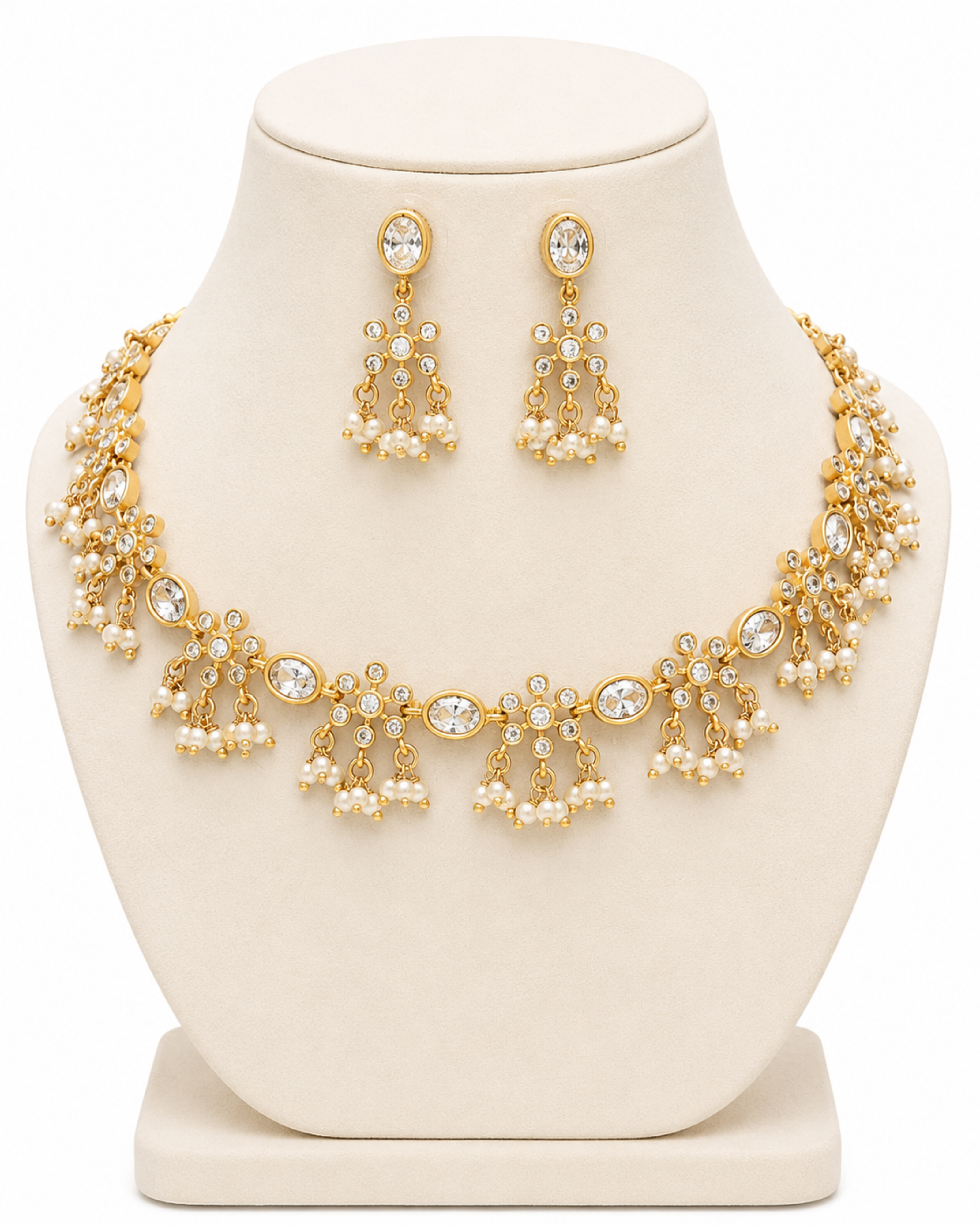 Gold necklace with pearls and matching earrings on a white stand