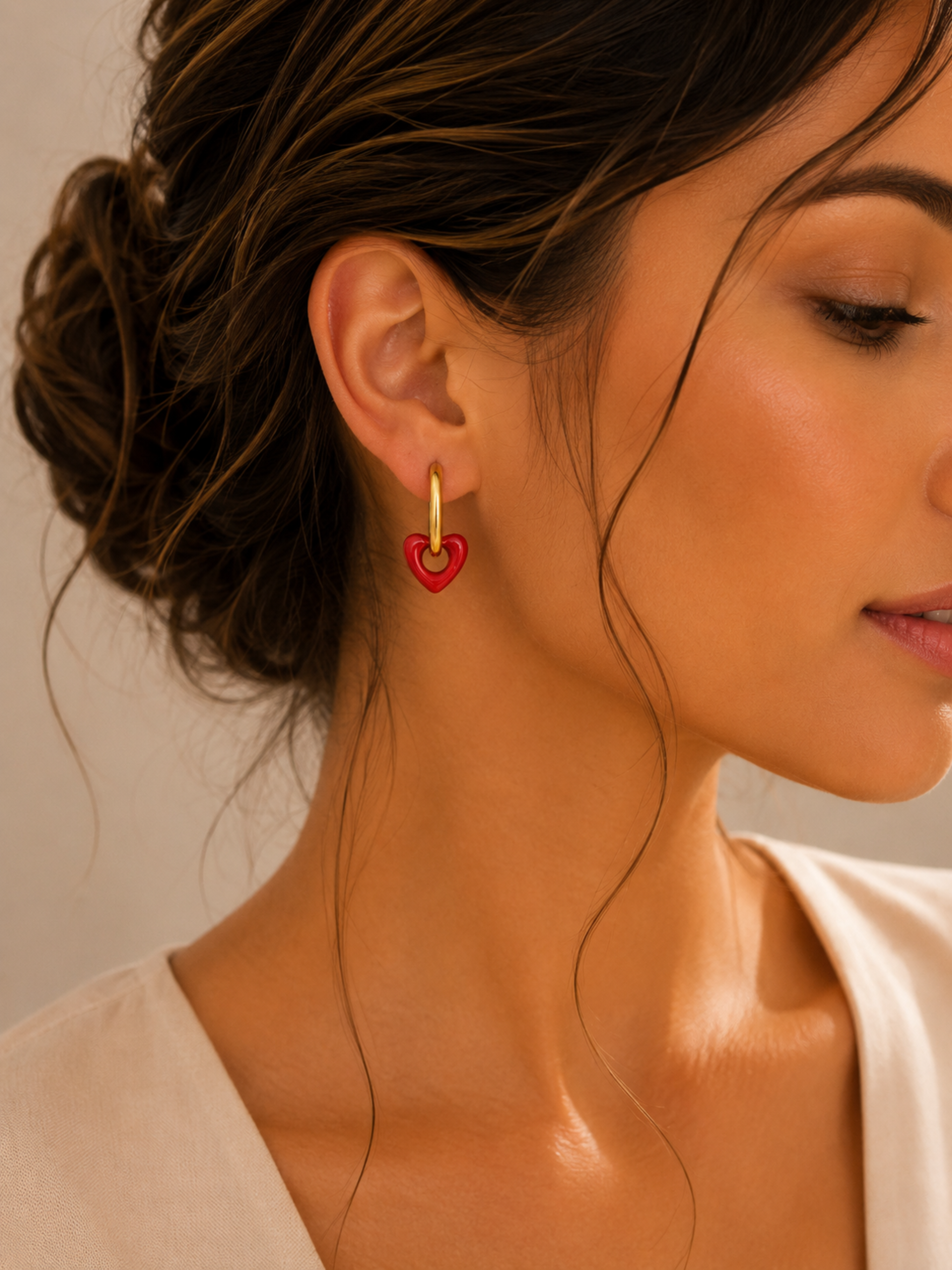 Close-up of a woman wearing a red heart-shaped earring with a neutral background