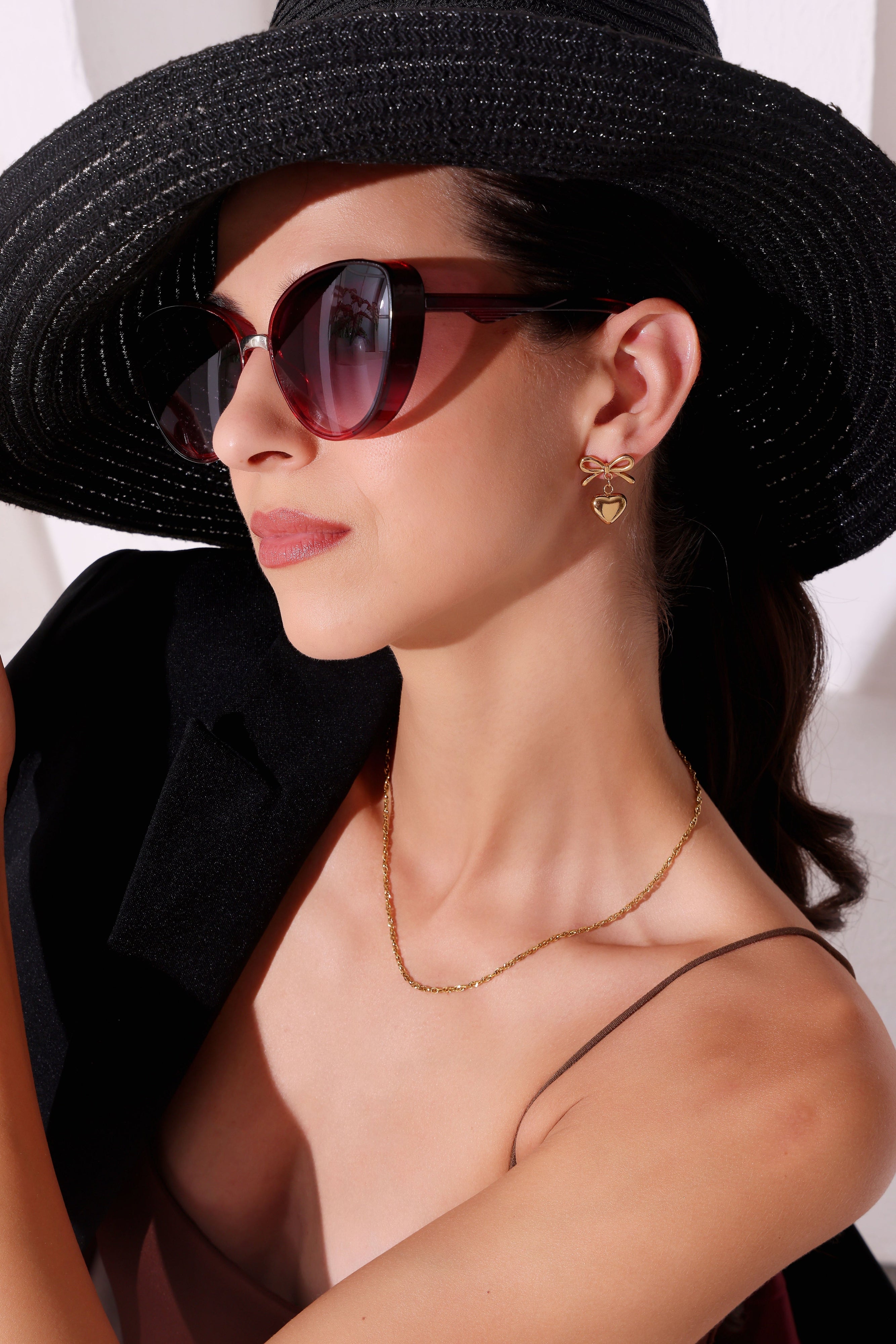 Woman wearing a black hat and sunglasses with a plain background