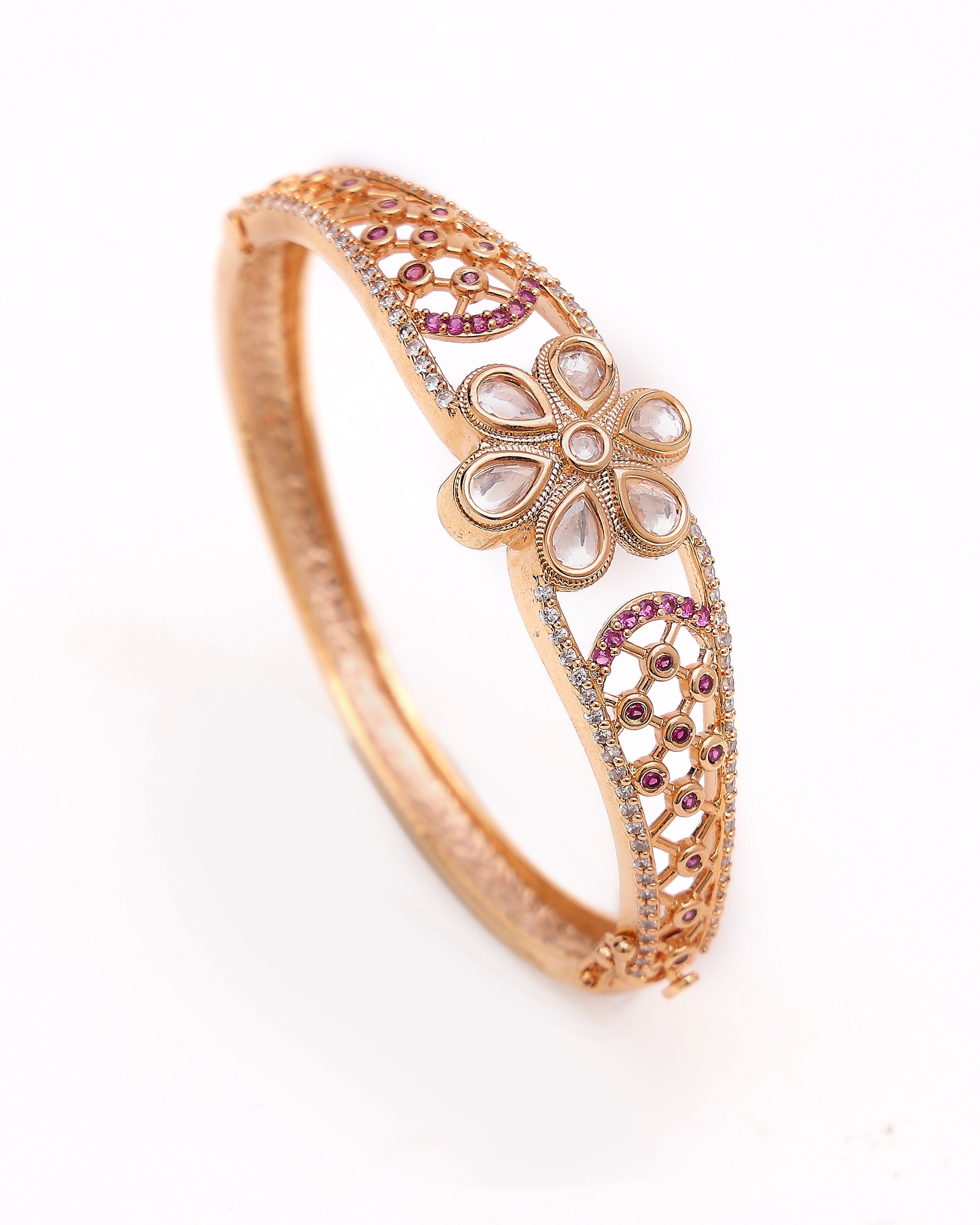 Rose gold bracelet with floral design and gemstones on a white background