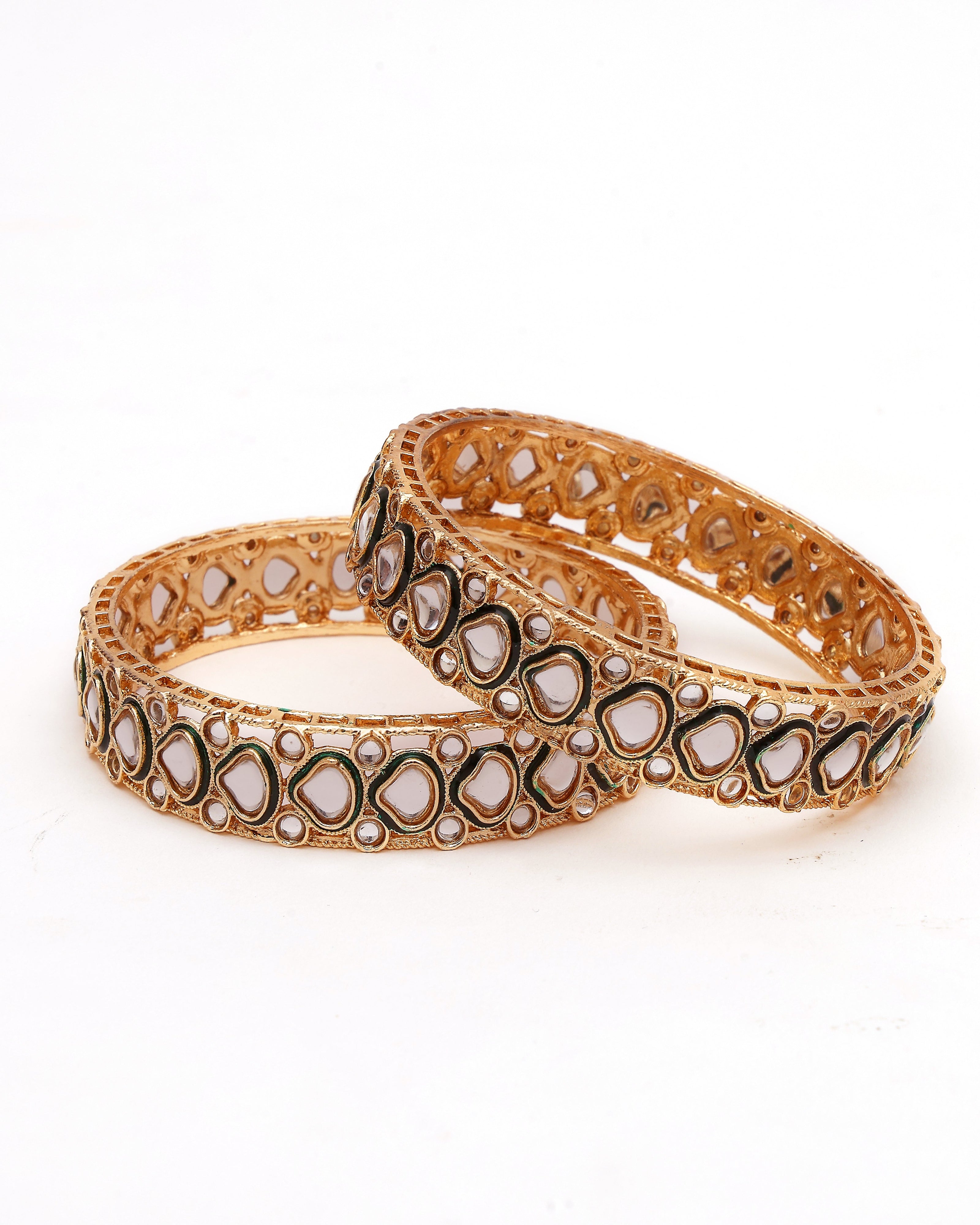 Pair of ornate gold bangles on a white background