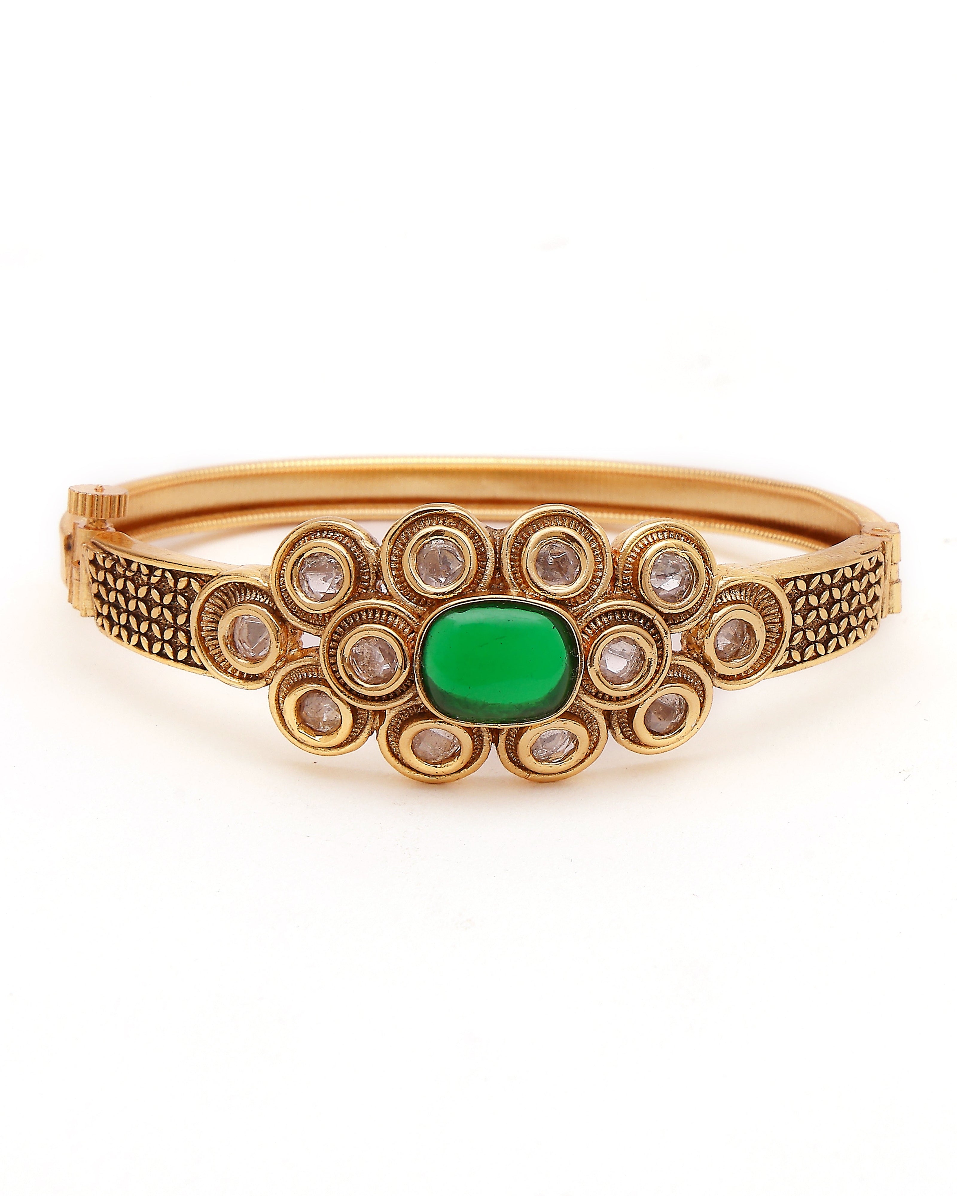 Gold bracelet with green gemstone on a white background