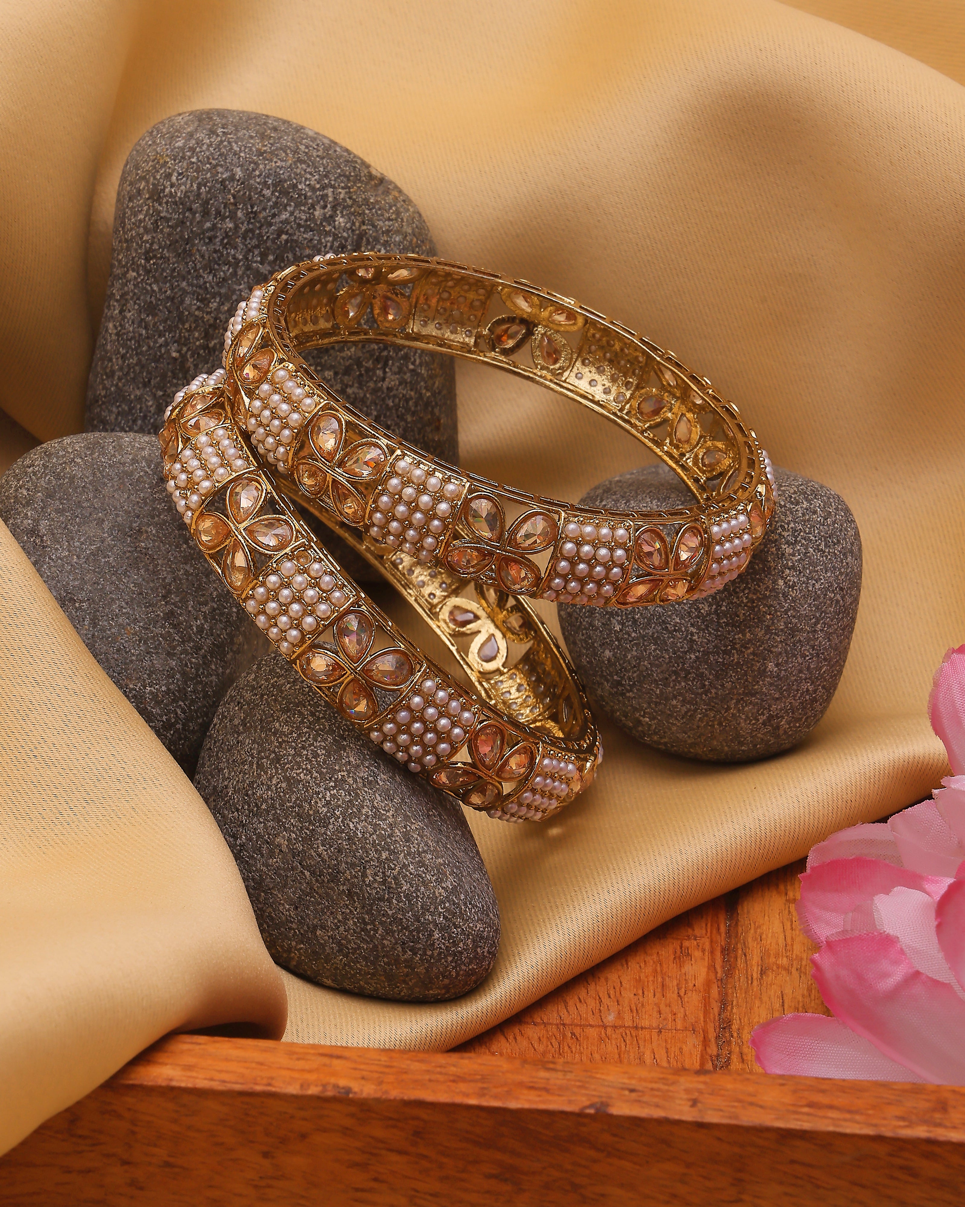 Gold bangles on stones with a soft background