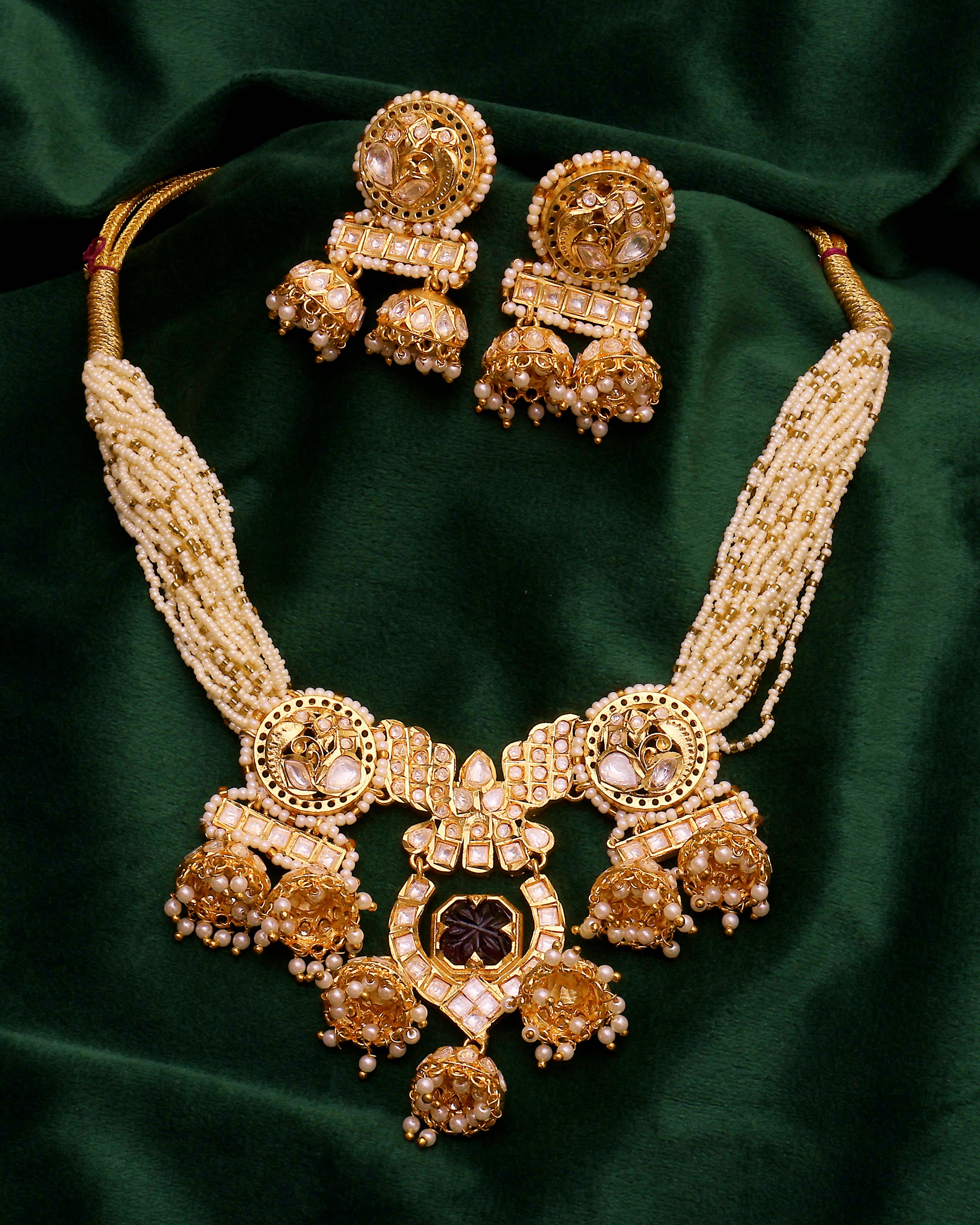 Gold necklace and earrings on a green fabric background