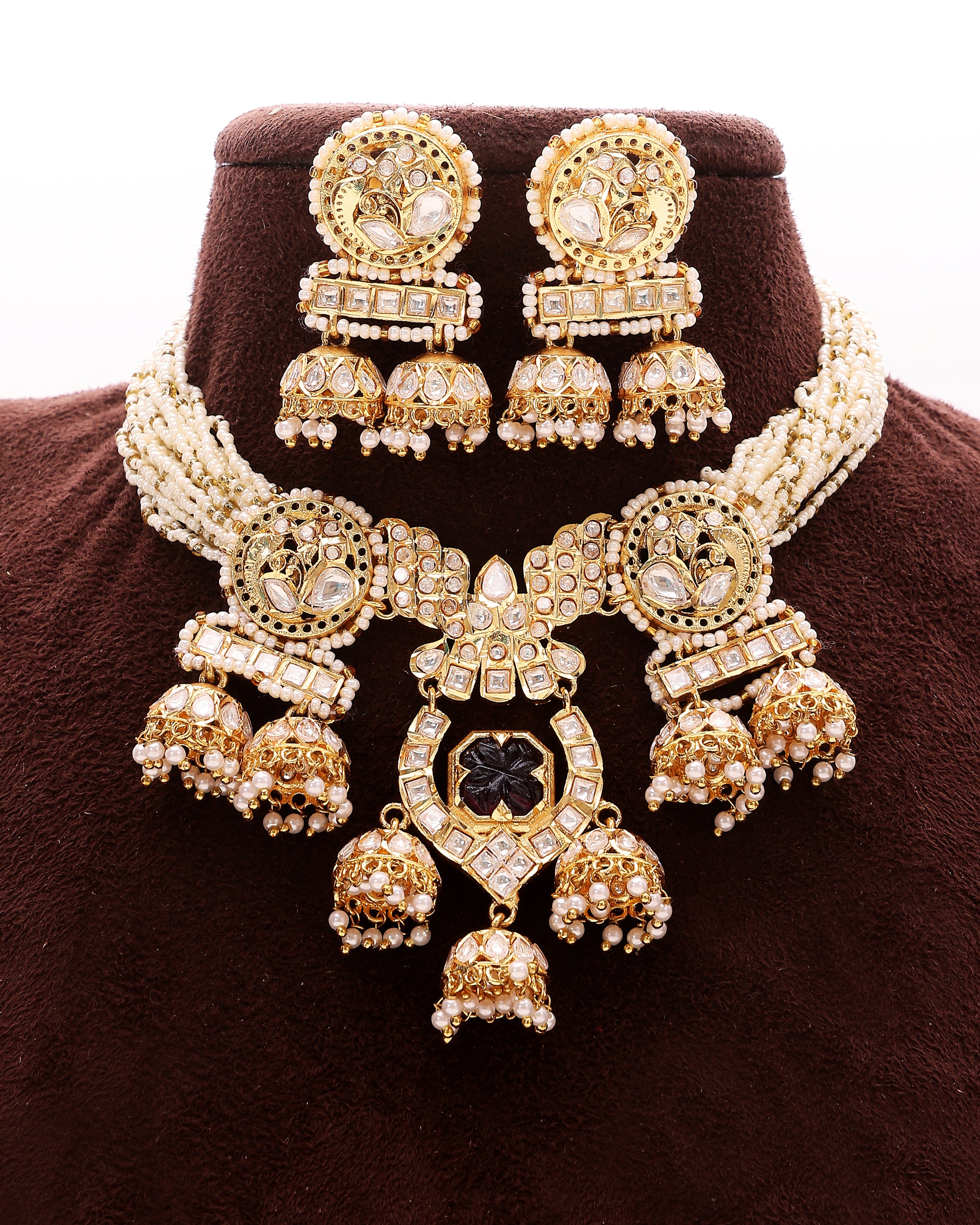 Gold jewelry set with necklace, earrings, and choker on a brown background