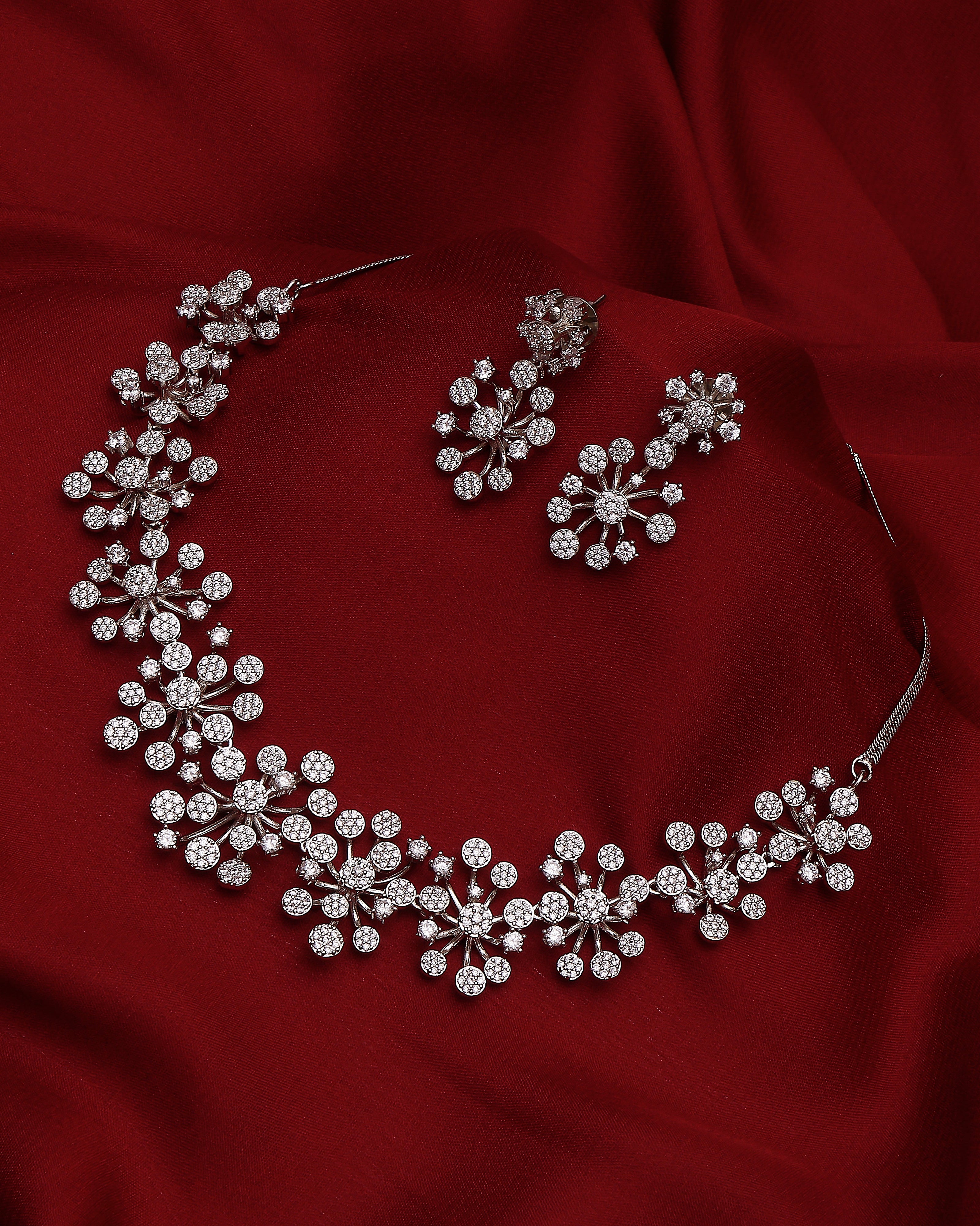 Silver necklace and earrings on a red fabric background