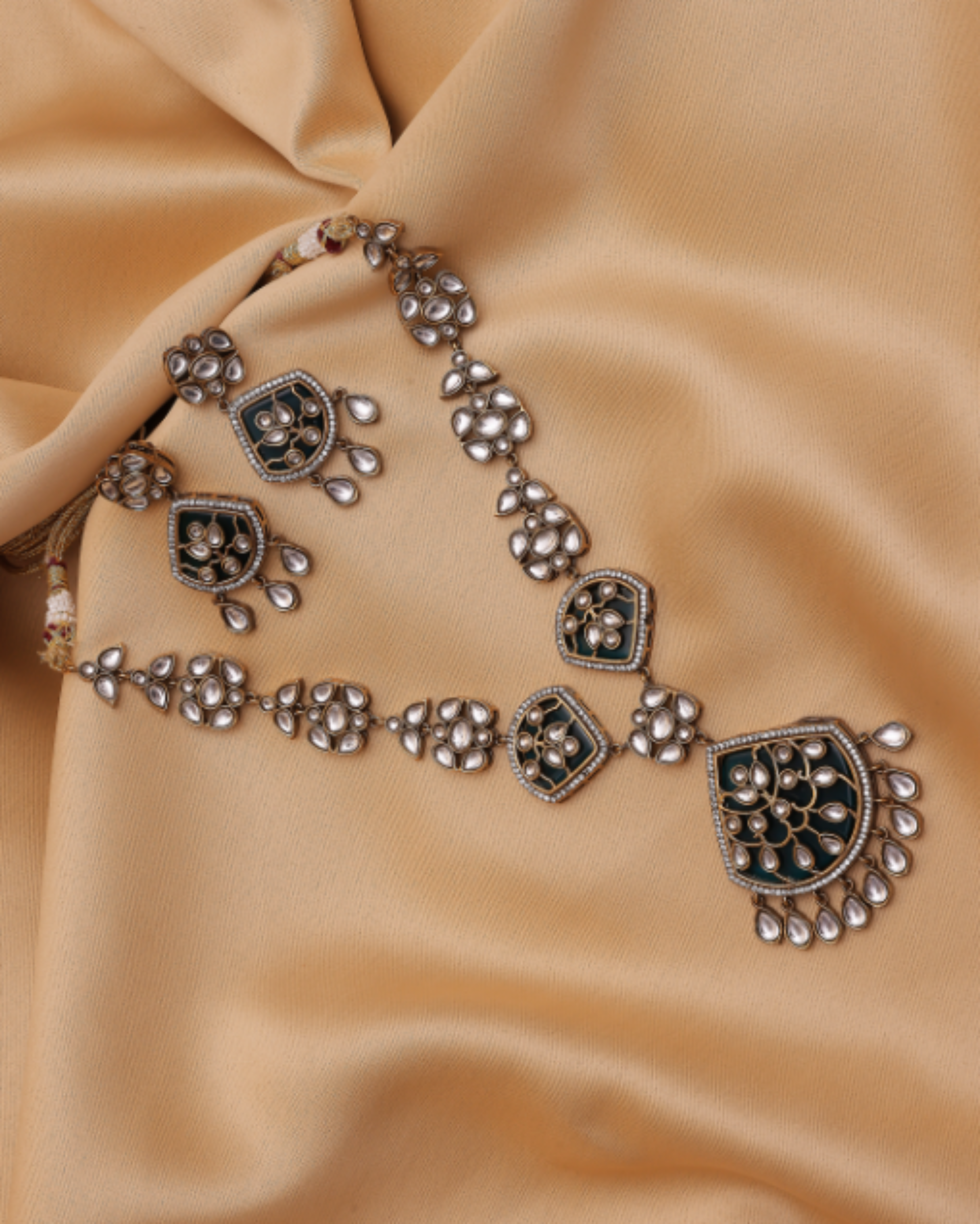Decorative silver necklace on a beige fabric background