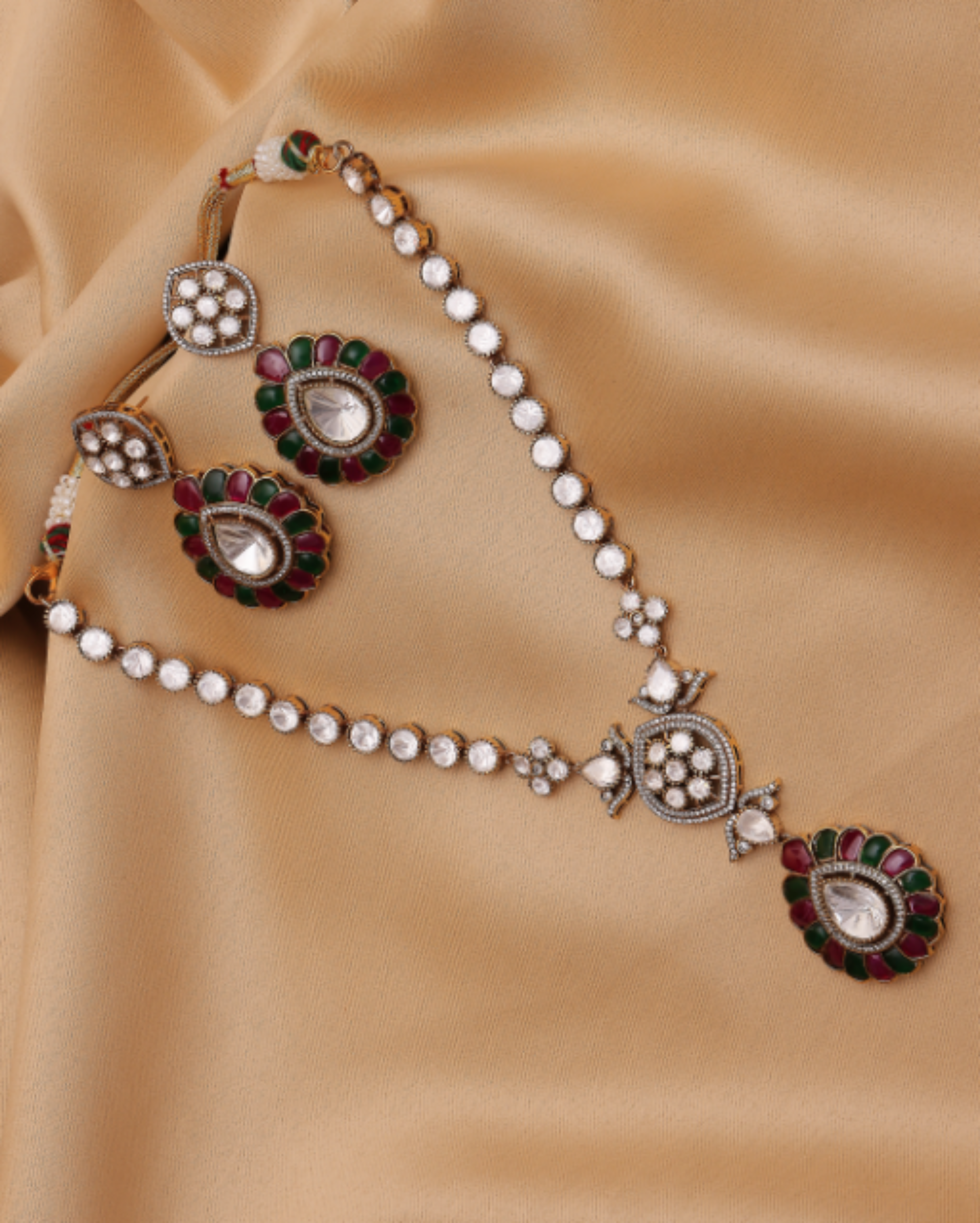 Ornate jewelry set with pearls and gemstones on a beige fabric background