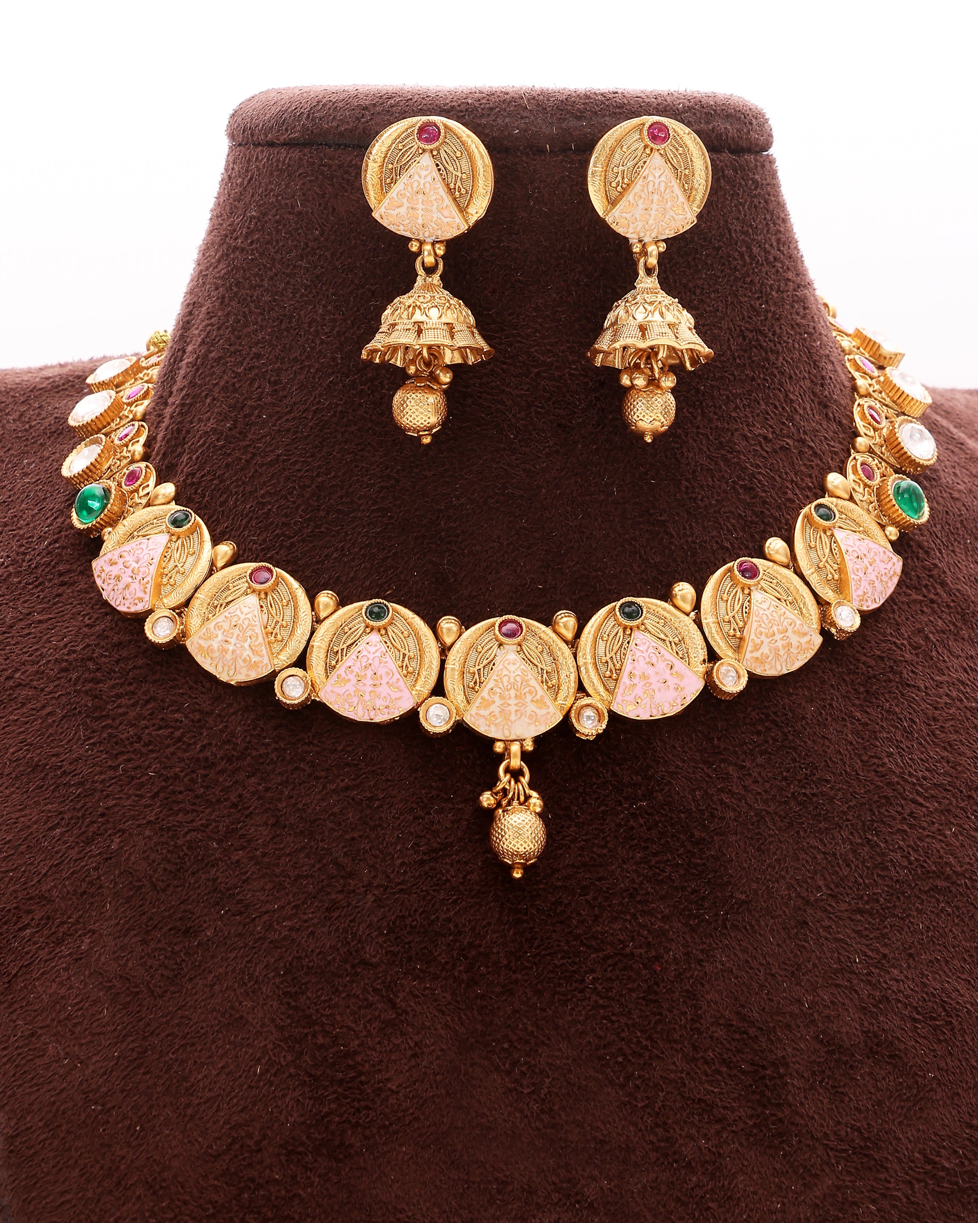 Gold necklace and earrings set on a brown stand
