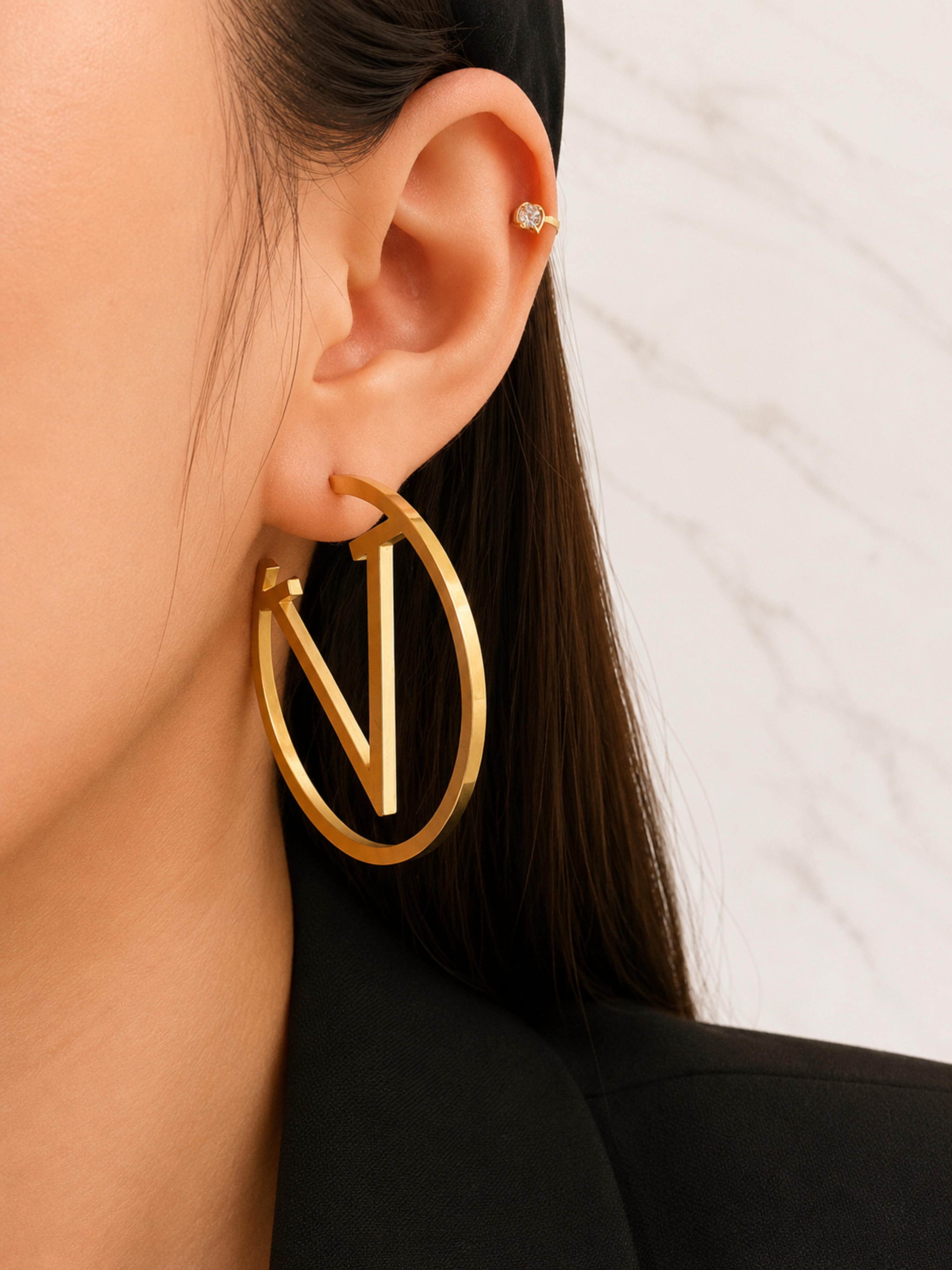 Gold hoop earring worn by a person with a neutral background