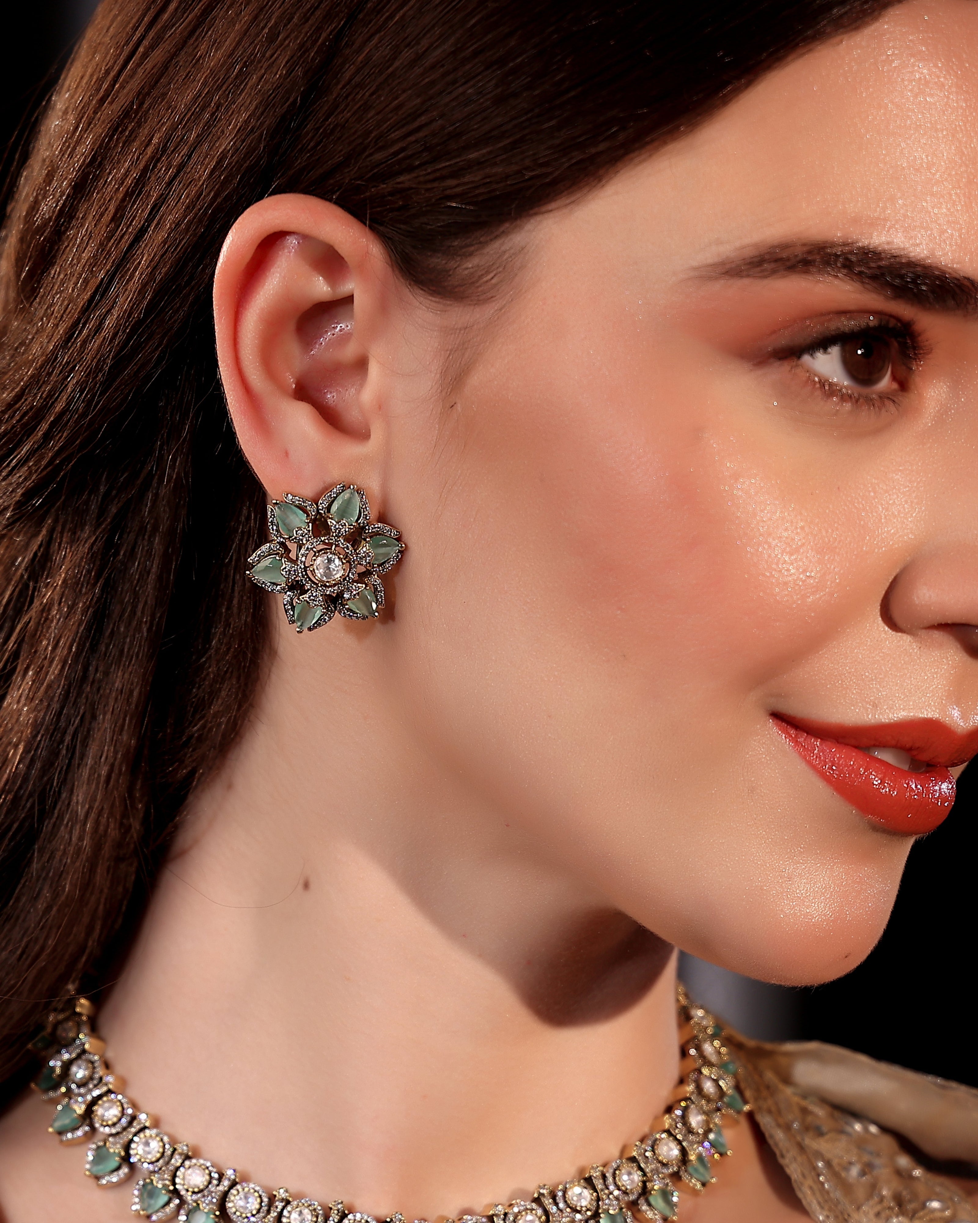 Close-up of a woman wearing a decorative earring and necklace.
