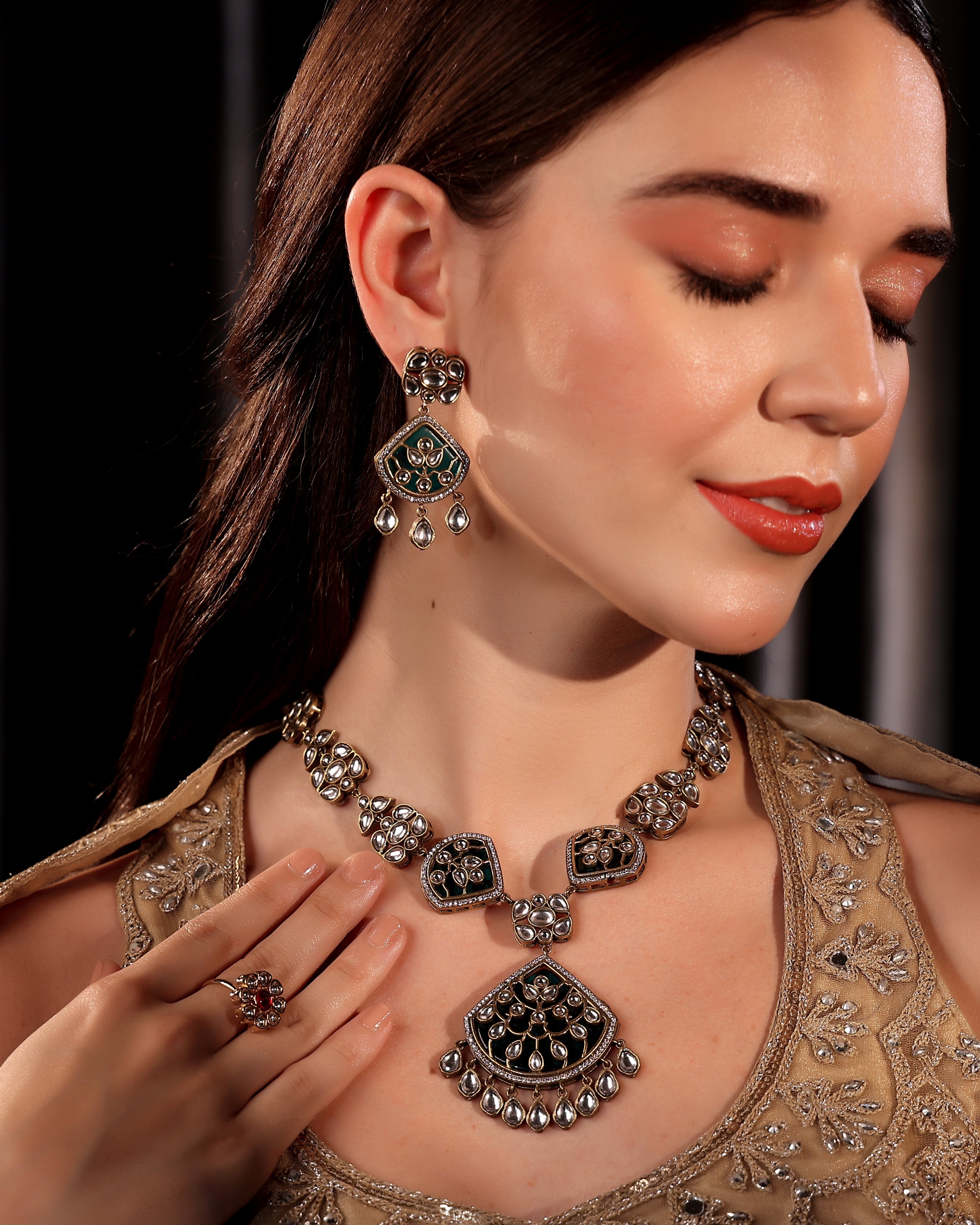 Woman wearing an ornate necklace, earrings, and ring with a dark background