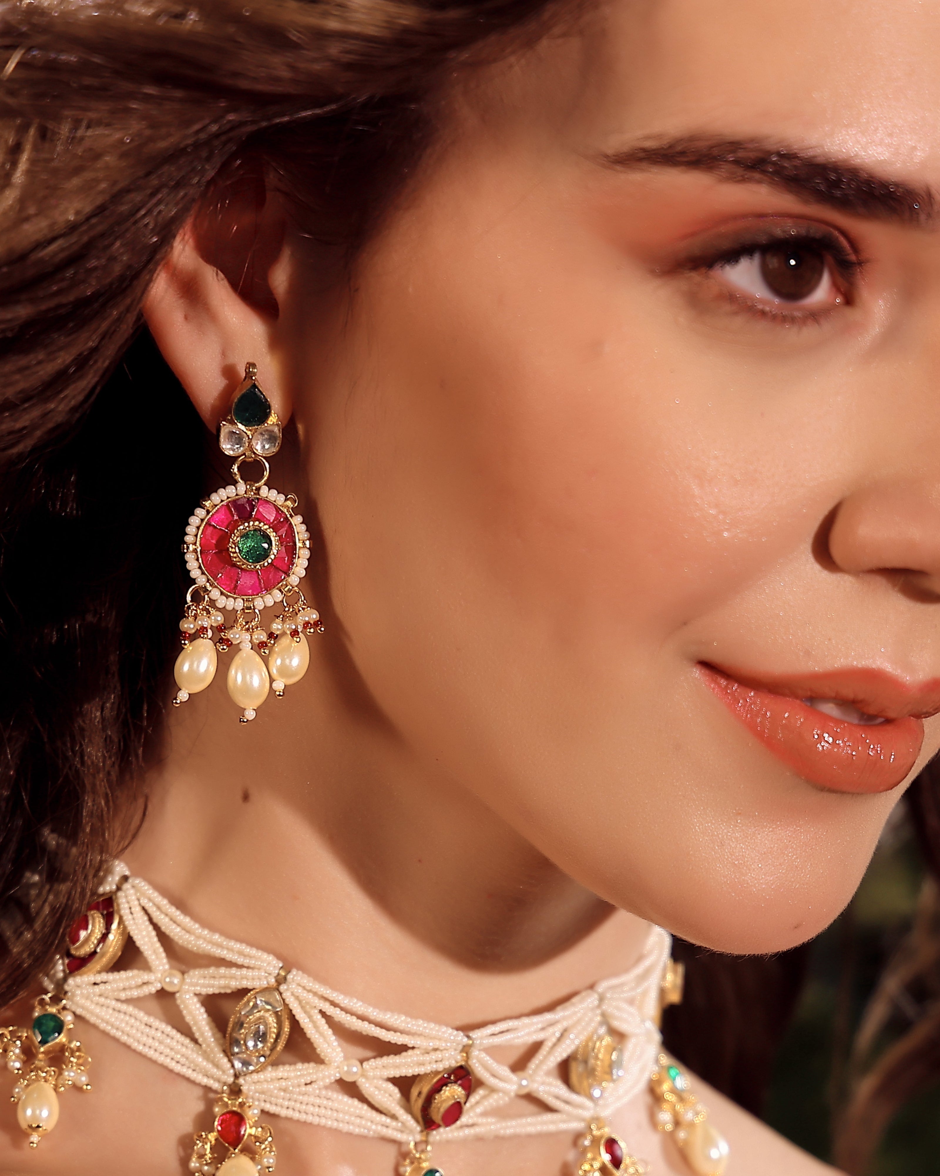Close-up of a woman wearing ornate earrings and a necklace with intricate designs.