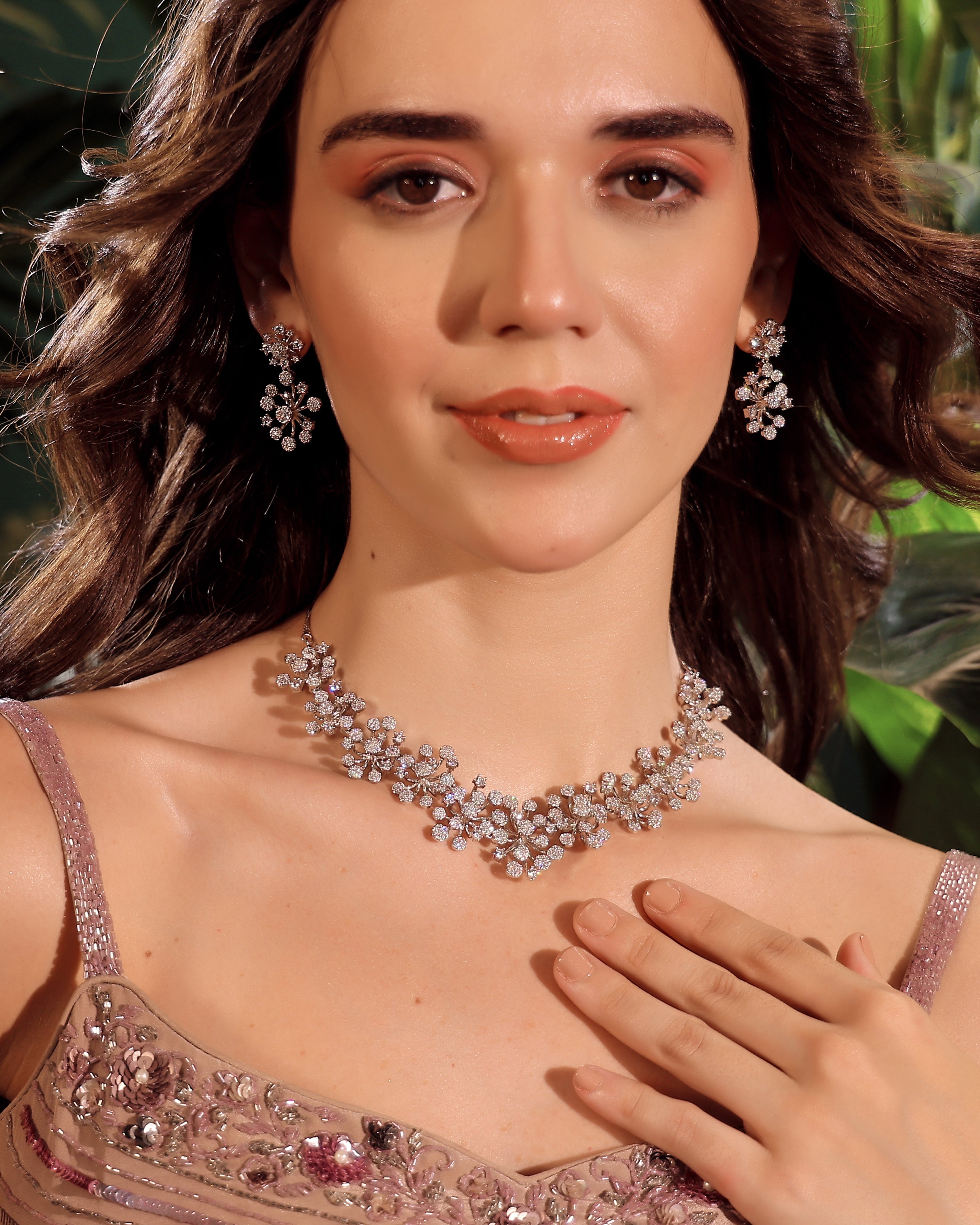 Woman wearing a sparkling necklace and earrings with a blurred green background