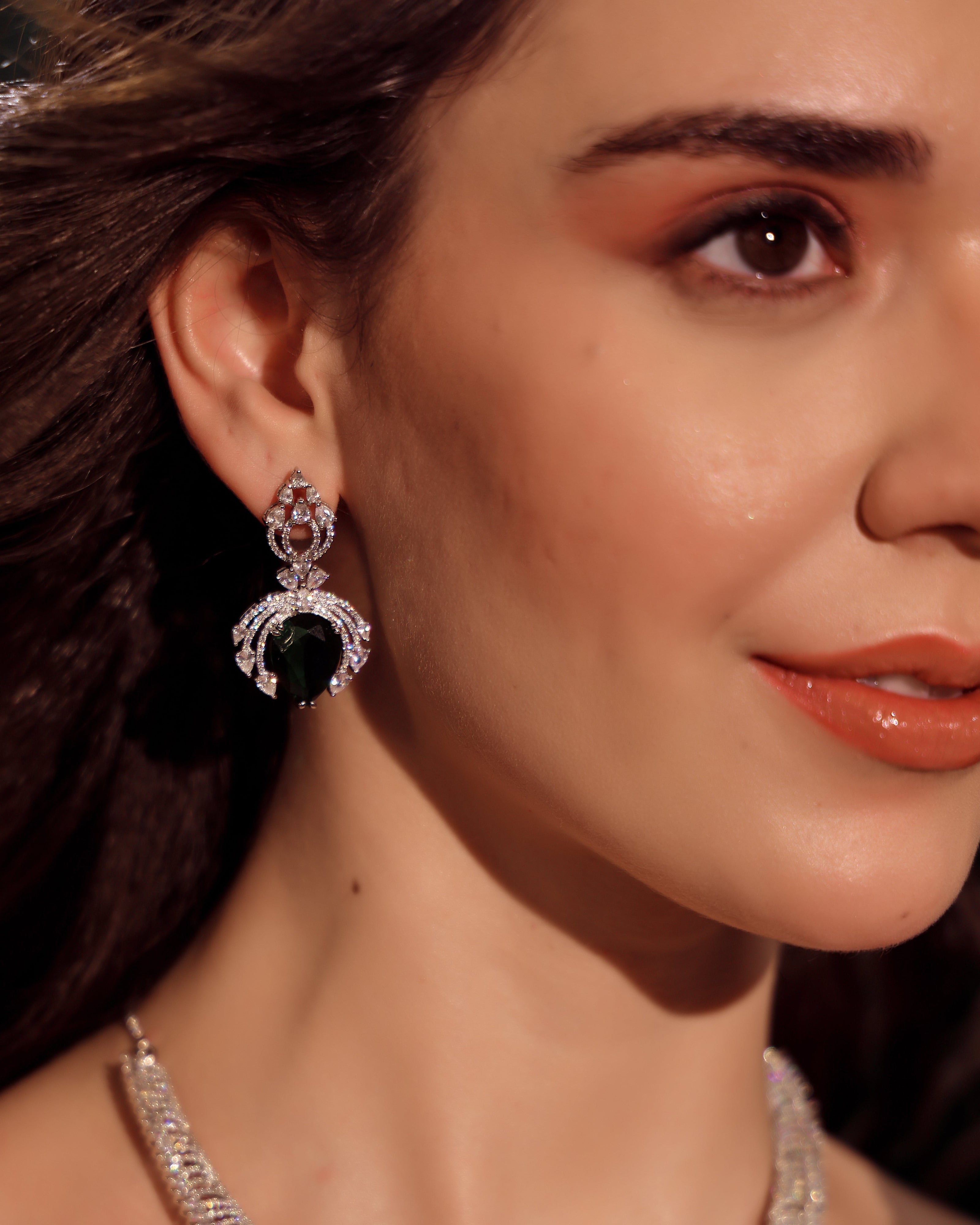 Close-up of a woman wearing a green gemstone earring with a blurred background
