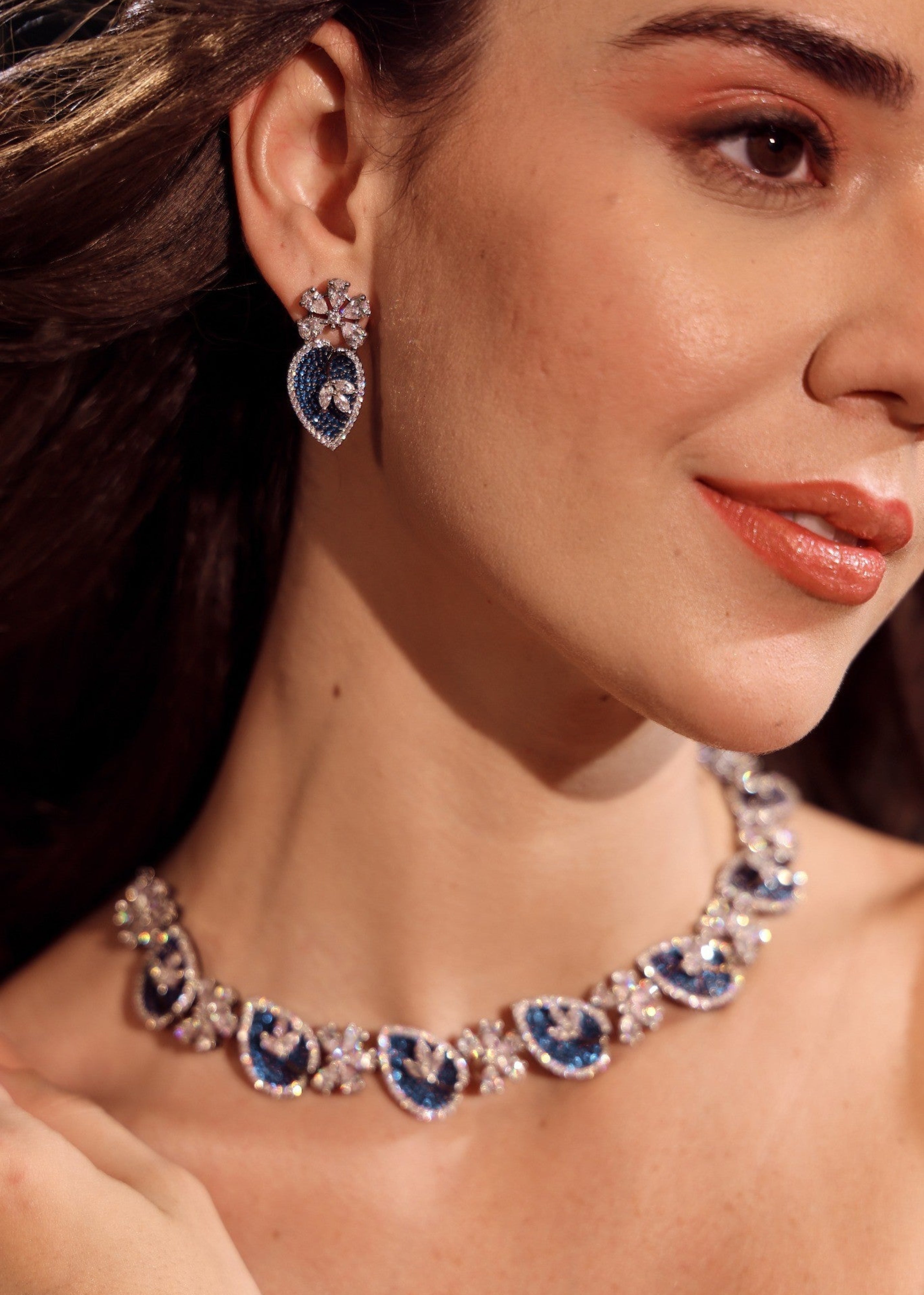 Close-up of a woman wearing a necklace and earrings with blue and silver accents.