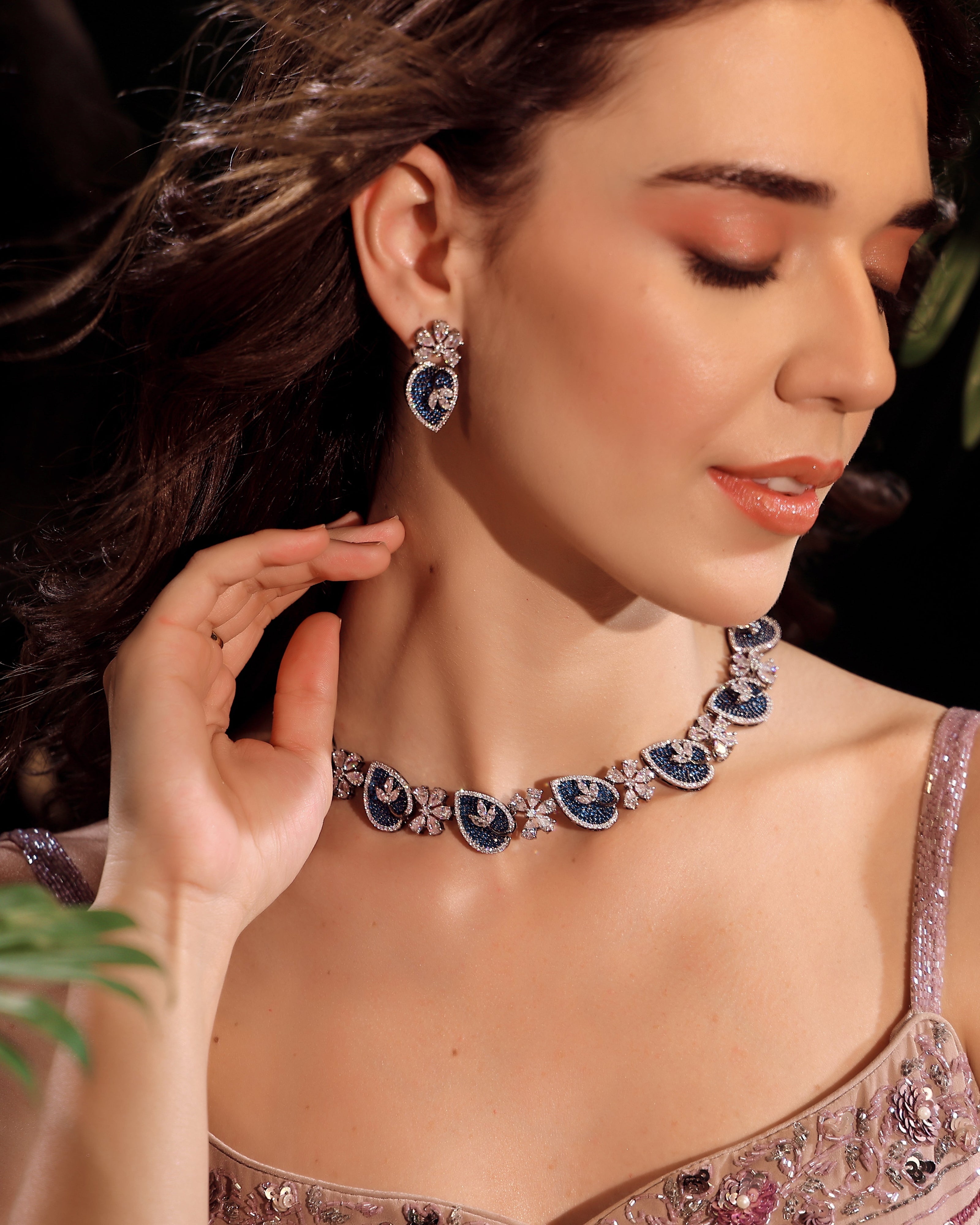 Woman wearing a blue and silver necklace and earrings against a dark background