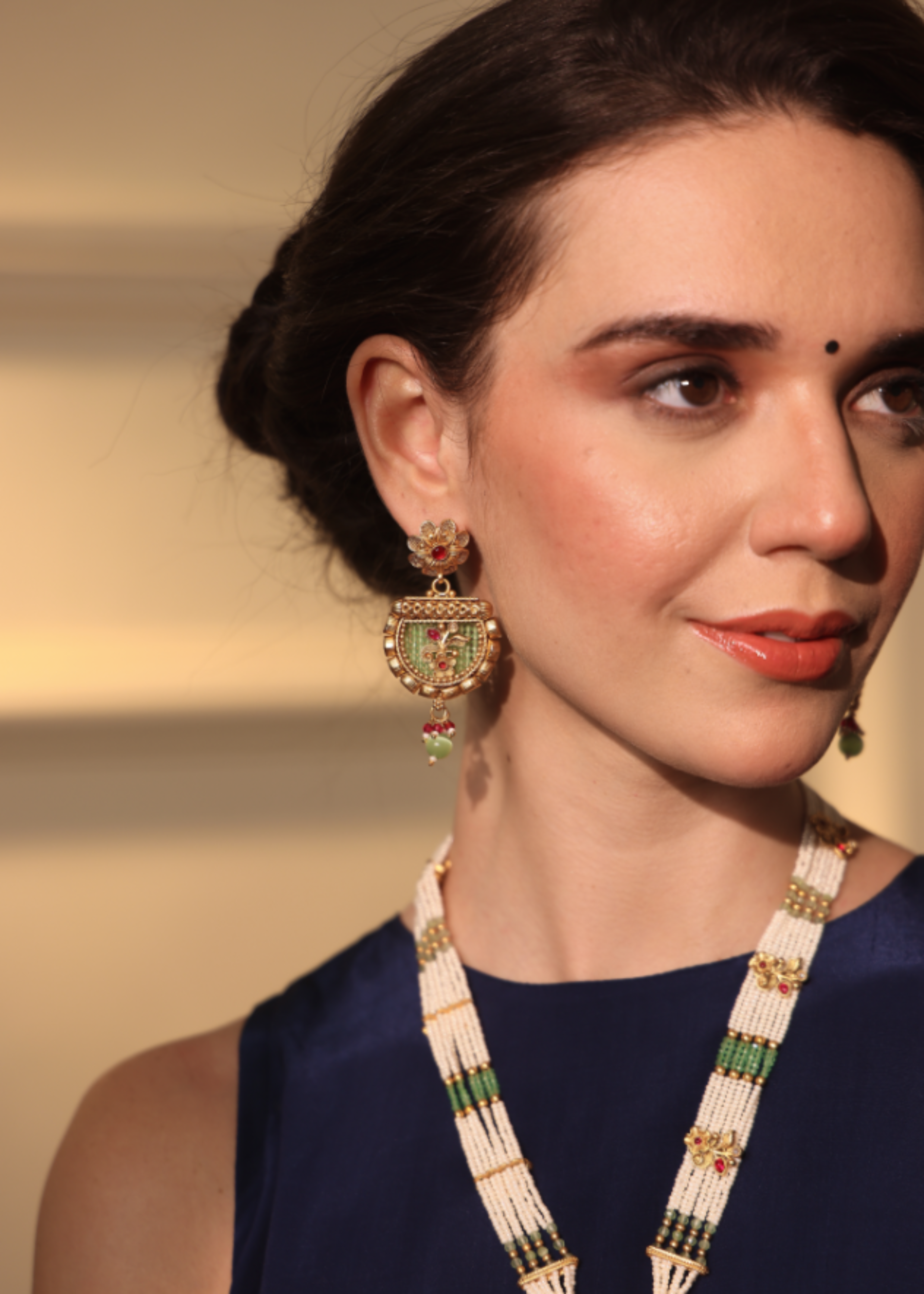 Woman wearing gold earrings and a necklace with a blurred background